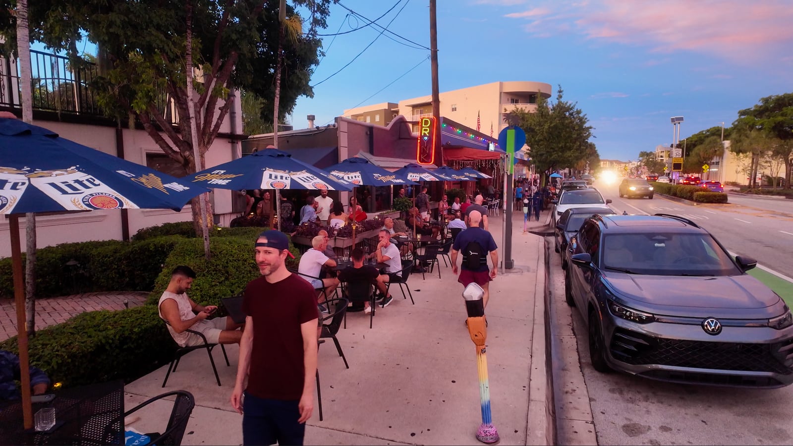Terrazas y peatones en Wilton Drive bajo un cielo de atardecer