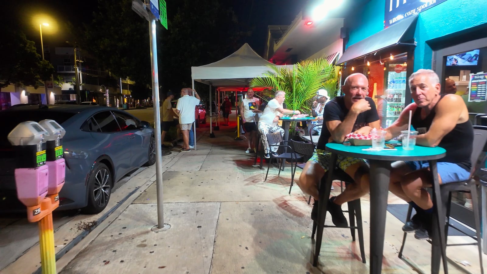 Dos personas sentadas a una mesa exterior durante la noche en Wilton Manors